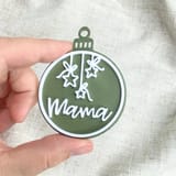 Eine Hand hält eine grüne Mama-Kugel mit Sternmotiv.