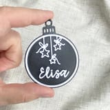 Eine Hand hält eine schwarze Elisa-Kugel.