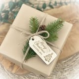 Personalisierter Holzanhänger an einem mit Schnur verschnürten Geschenk.