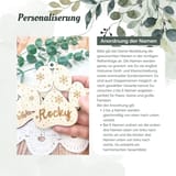 Könnte beinhalten: Ein helles Holzornament in Pfotenform mit eingravierten Schneeflockenmotiven und dem Namen Rocky. Der Text Personalisierung und Anordnung der Namen erscheint zusammen mit Anweisungen zur Bestellung von individuell gravierten Namen auf dem Ornament.