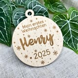 Holzanhänger Mein erstes Weihnachten mit dem Namen Henry und der Jahreszahl 2025 vor Efeublättern