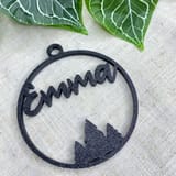 Schwarze Weihnachtskugel mit dem Namen Emma und Tannenmotiv vor Efeu