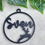 Schwarze Weihnachtskugel mit dem Namen Sven und Rentiermotiv vor Efeu