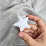 Weißer Weihnachtsstern in einer Hand vor hellem Stoff