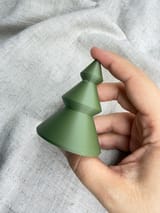 Grüner Tannenbaum in einer Hand vor hellem Stoff