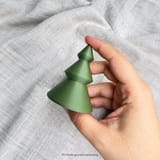 Weißer Tannenbaum in einer Hand vor hellem Stoff
