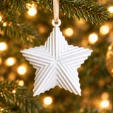 Weißer Kissenstern Rippenstrick am beigen Band durch die Öse im Weihnachtsbaum hängend – KI-bearbeitet nach Originalfoto