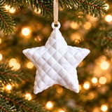 Weißer Kissenstern Steppkissen am beigen Band durch die Öse im Weihnachtsbaum hängend – KI-bearbeitet nach Originalfoto