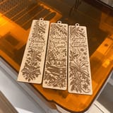 Drei ausgeschnittene winterliche Lesezeichen auf dem orangefarbenen Laserdeckel – quadratische, KI-bearbeitete Fotofassung.