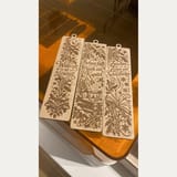 Drei ausgeschnittene und gravierte winterliche Holz-Lesezeichen auf dem orangefarbenen Laserdeckel, Originalfoto.