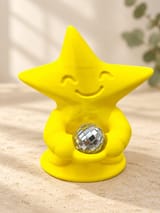 KI-bearbeitetes Produktbild: Gelbe Tanzfunke-Sternfigur mit lächelndem Gesicht und separater silberner Mini-Discokugel auf hellem Kalkstein vor cremefarbenem Hintergrund.