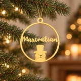 Goldfarbener Christbaumanhänger mit Namen und Schneemann am Tannenzweig