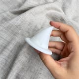Weißer Hexenhut mit breiter Krempe in einer Hand