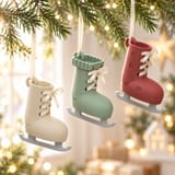 Drei Deko-Schlittschuhe in Creme, Grün und Rot an Tannenzweigen